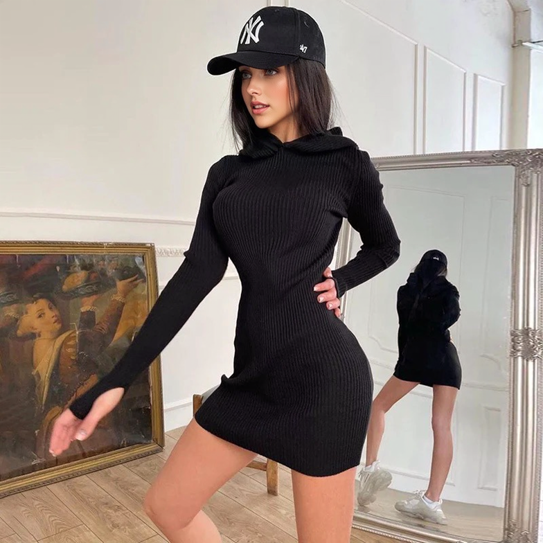 A woman wearing a black ribbed knit hooded dress and a baseball cap.