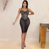 A woman in a black rhinestone-embellished sheer dress with a sweetheart neckline and halter straps.