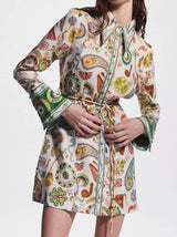 Close-up of a woman adjusting the belt on a colorful paisley print shirt dress.