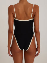 Back view of a woman in a black one-piece swimsuit with white trim