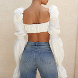 Back view of a woman wearing a white crop top and blue jeans