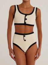 Woman wearing a cream and black ribbed bikini with high-waisted bottoms and a scoop neck top with button details