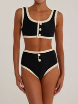 Woman wearing a black and cream ribbed bikini with high-waisted bottoms and a scoop neck top with button details