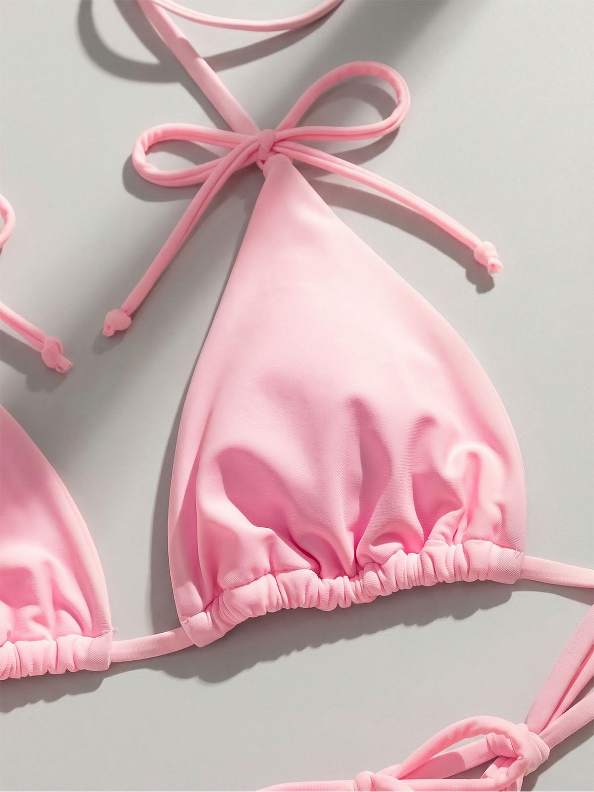 Close-up of a pink bikini top with ruched cups and adjustable ties