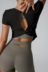 Woman wearing a black cropped top with an open back and olive green shorts