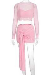 A pink sheer long-sleeved crop top and a pink ruched mini skirt with a tie detail displayed on a mannequin.