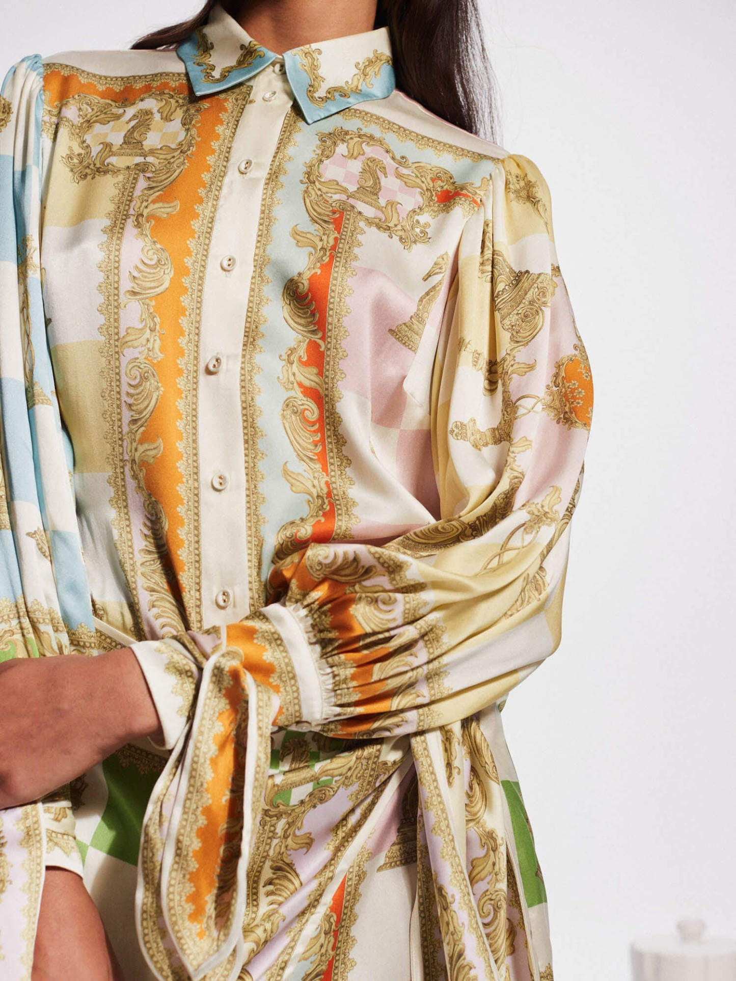 close-up of the sleeve of a white, green, orange, blue, pink, and yellow patterned silk shirt dress with a tie waist and puffed sleeves
