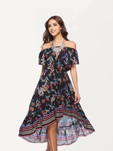 A woman smiles while modeling a black off-the-shoulder dress with a floral print and a high-low hem.