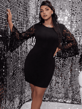 A woman in a black dress with lace sleeves leans against a wall.