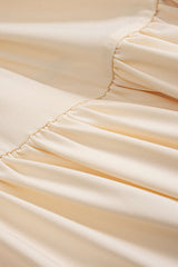 Close-up of the ruched detailing and fabric of a cream maxi dress