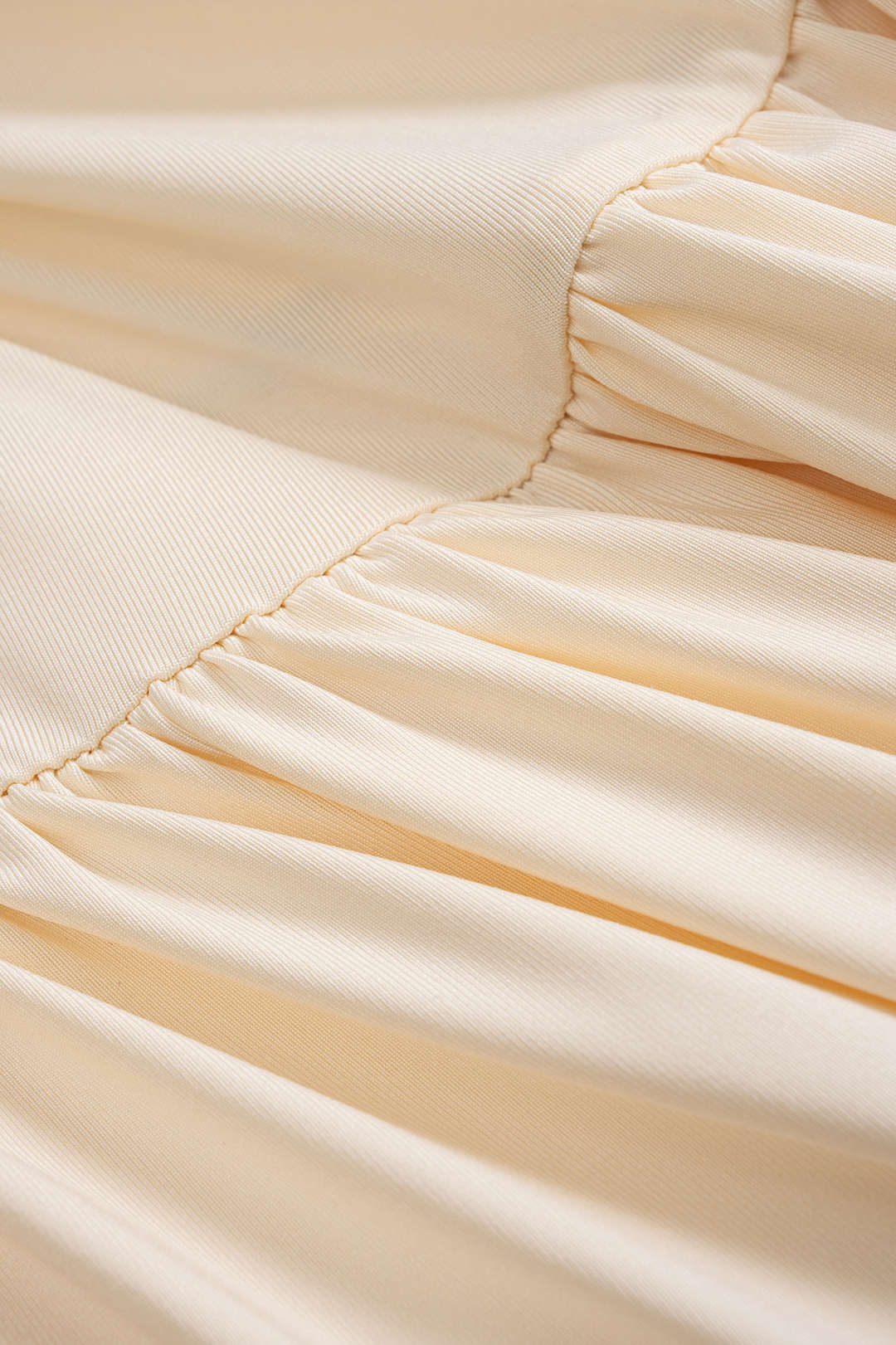Close-up of the ruched detailing and fabric of a cream maxi dress