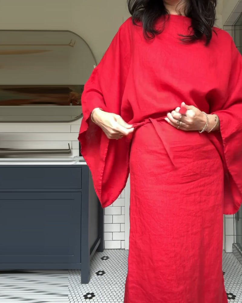 Close-up of a woman tying the belt of her red linen dress.