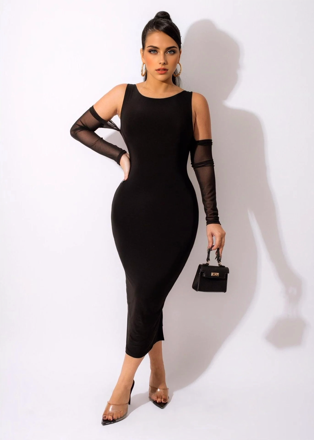 A woman in a black midi dress with sheer sleeves and a side slit, posing for a product shot.
