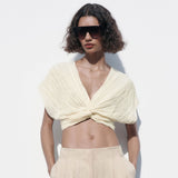 woman wearing a cream twisted crop top and beige pants