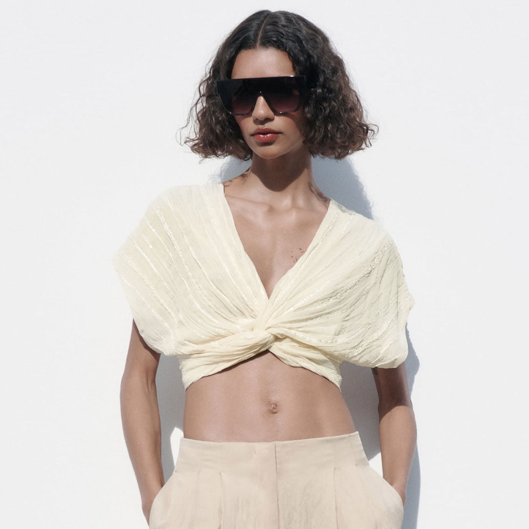 woman wearing a cream twisted crop top and beige pants
