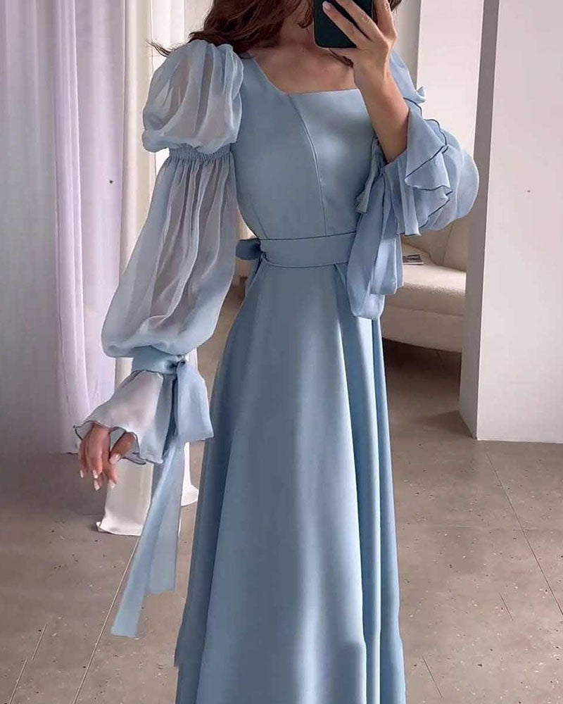 Close-up of the light blue satin dress, highlighting the puff sleeves and ruffled cuffs.