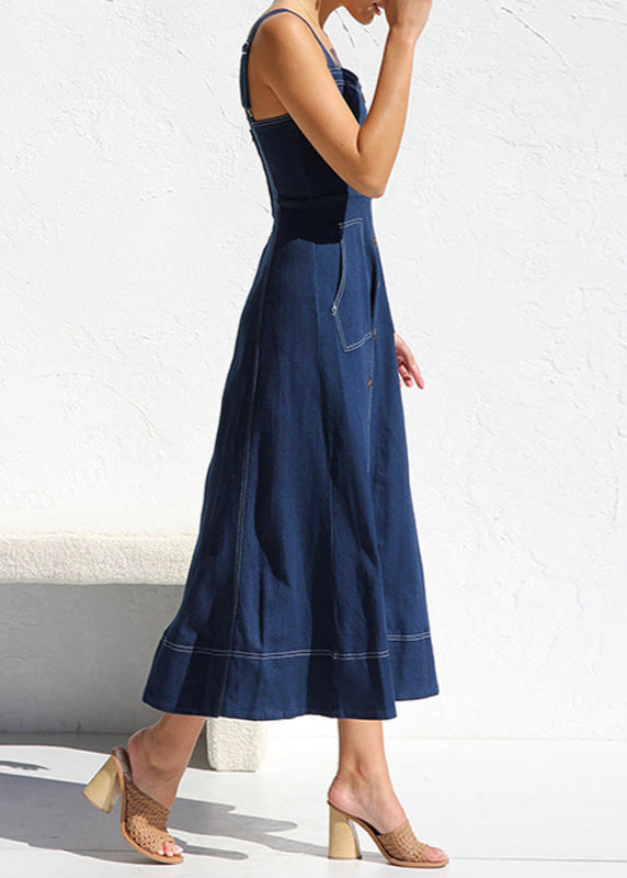 Side view of a woman walking in a dark blue denim midi dress, highlighting the A-line silhouette and the detail of the contrast stitching.