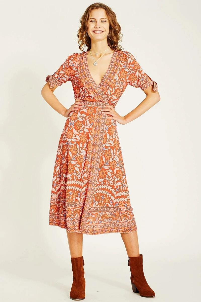 woman in orange floral wrap dress and brown boots