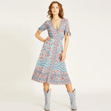 woman in blue floral wrap dress and grey boots