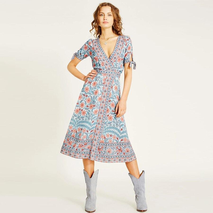 woman in blue floral wrap dress and grey boots