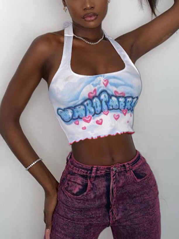 A woman with dark skin wearing a white halter neck crop top with a blue and pink graphic print and pink hearts, paired with purple acid wash jeans.