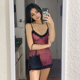 Woman wearing a pink leopard print slip dress with black lace trim and a black handbag, taking a mirror selfie.