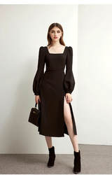A woman in a black midi dress with a square neckline and puff sleeves, holding a black handbag.