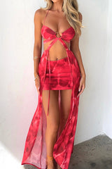 Woman modeling a red tie-dye print two-piece set featuring a halter top and a mini skirt with a sheer maxi overlay.