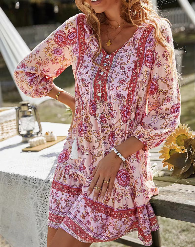 Woman in a pink floral print dress with hands on hips, outdoors.