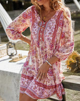 Woman in a pink floral print dress with hands on hips, outdoors.