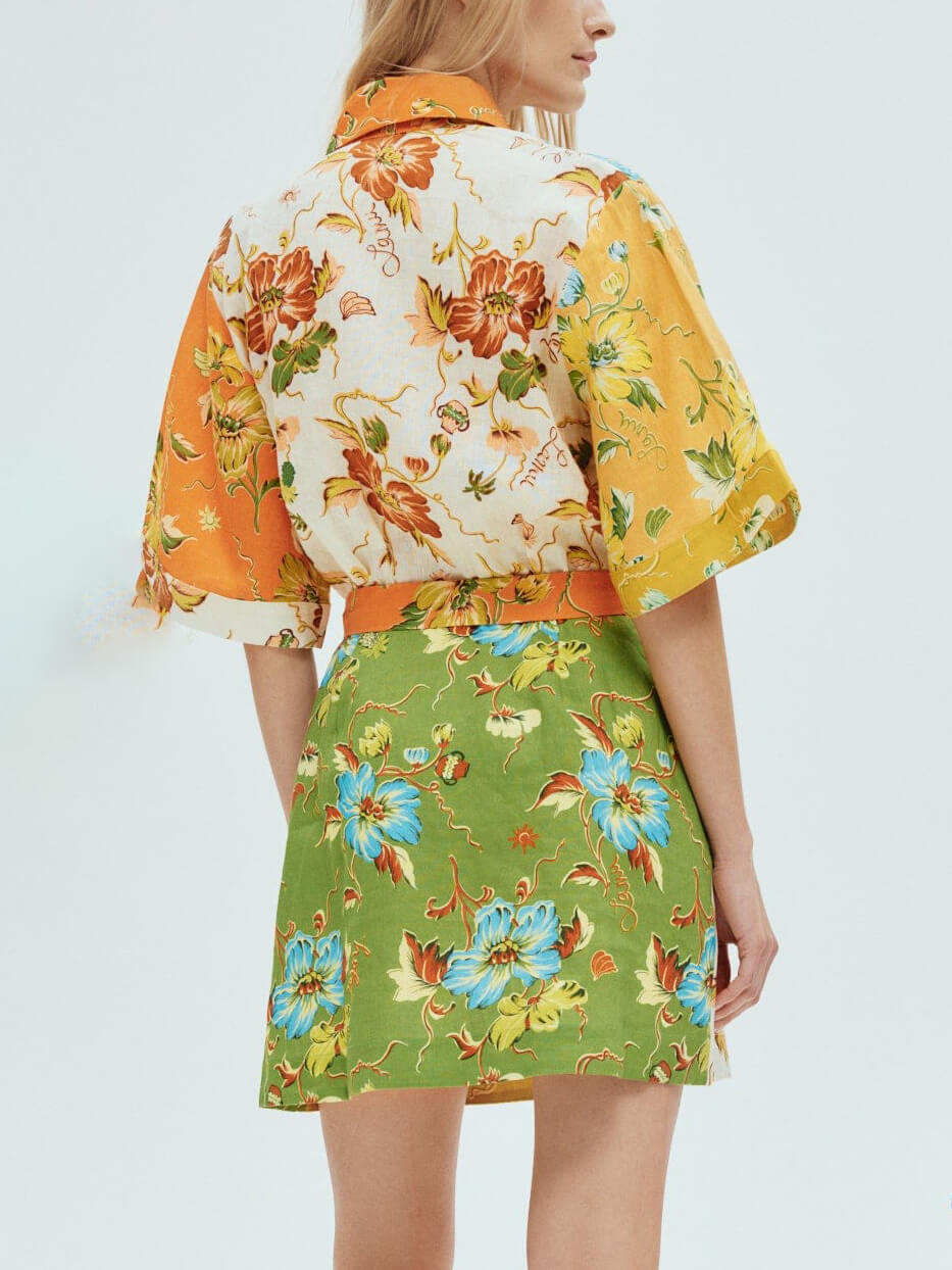 Back view of a woman wearing a floral print shirt dress with short sleeves and a belted waist.