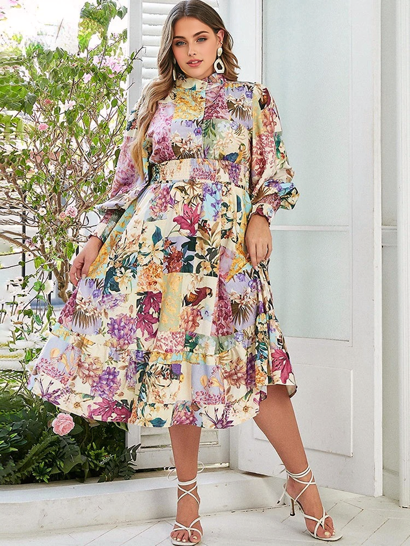 A woman poses in a floral print dress with bishop sleeves and a smocked waist, showing off the tiered skirt.