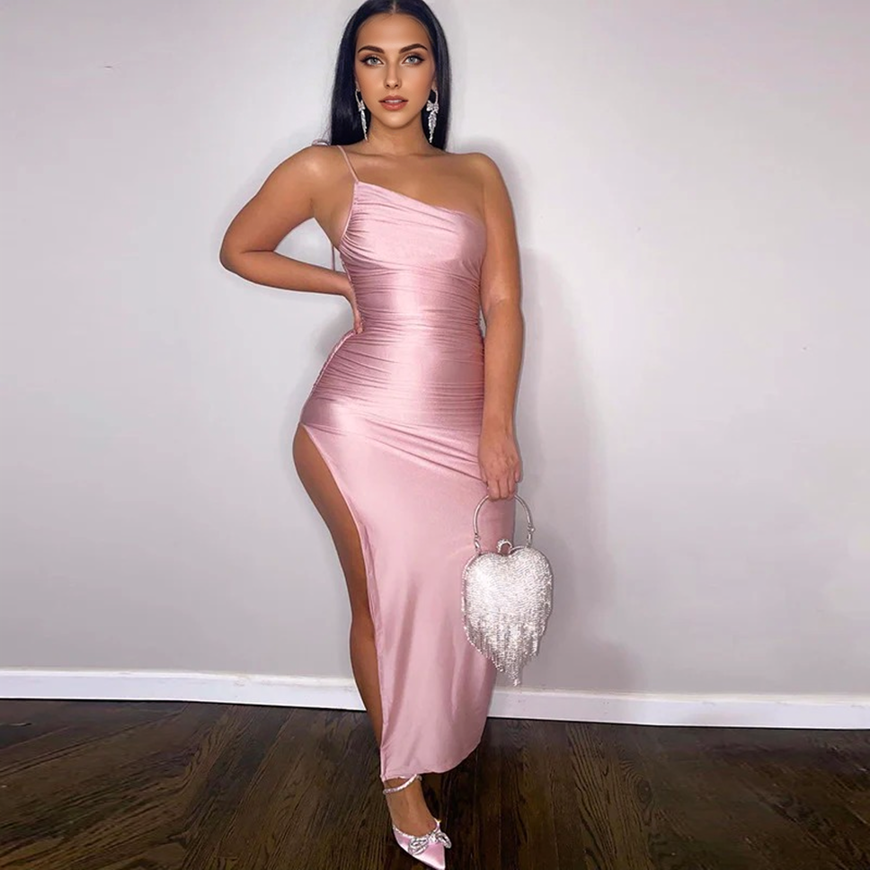 Woman in a pink ruched one-shoulder dress with a high slit, holding a heart-shaped clutch