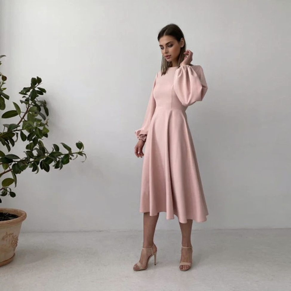 woman wearing a pink midi dress with bishop sleeves and high heels