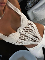 Close-up of a woman wearing a cream knit top with a crochet overlay and white pants.