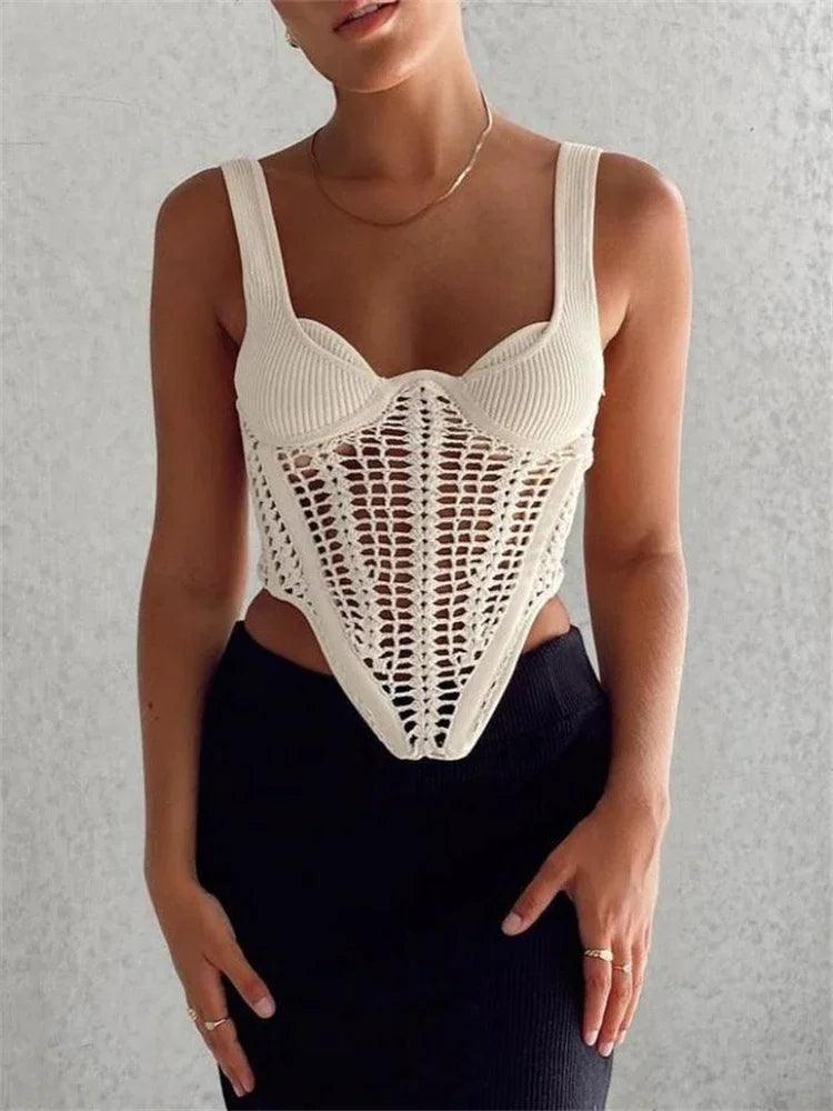 A woman in a cream knit top with a crochet overlay and a black skirt.