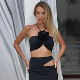 woman wearing a black halter top with a rose detail and a black maxi skirt with a cutout