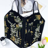 Close-up of a black floral embroidered corset top with lace trim and hook-and-eye closure.