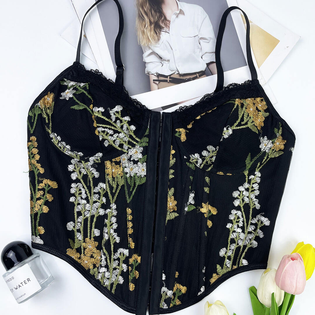 Close-up of a black floral embroidered corset top with lace trim and hook-and-eye closure.