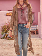 A woman wearing a brown lace kimono over a dusty rose tank top and blue jeans.