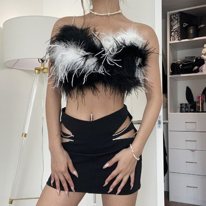 A woman in a black and white feathered crop top with cut-out details on the skirt.