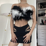 A woman in a black and white feathered crop top with cut-out details on the skirt.