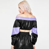 Back view of a woman wearing a black and purple off-the-shoulder cropped jacket with matching black pants.