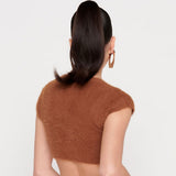 Back view of a woman wearing a brown fuzzy cropped cardigan, showing her ponytail and earrings.