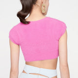 back view of a woman wearing a bright pink fuzzy cropped cardigan