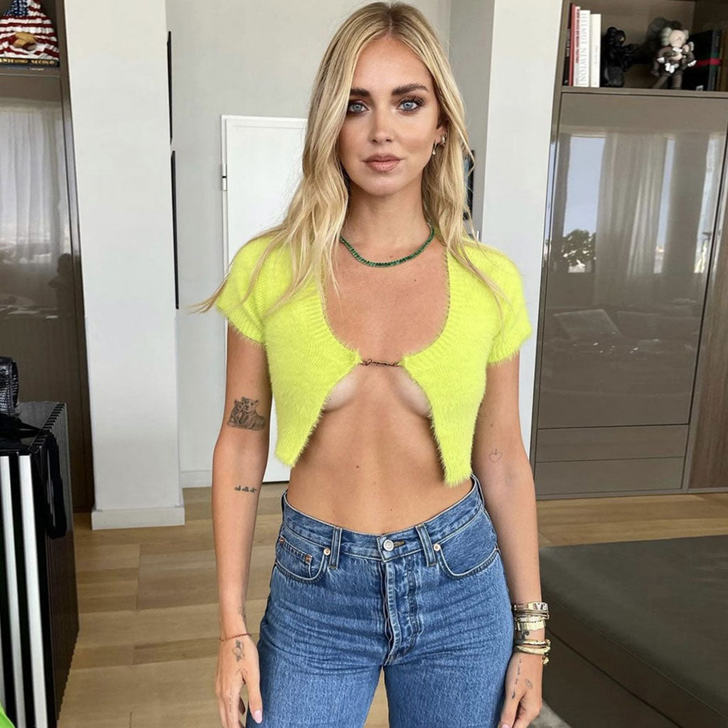Woman wearing a lime green fuzzy cropped cardigan over blue jeans.