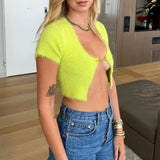 Side view of a woman wearing a lime green fuzzy cropped cardigan and blue jeans.