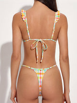 Back view of a woman wearing a colorful gingham bikini with ruffle trim on the straps and a tie closure.