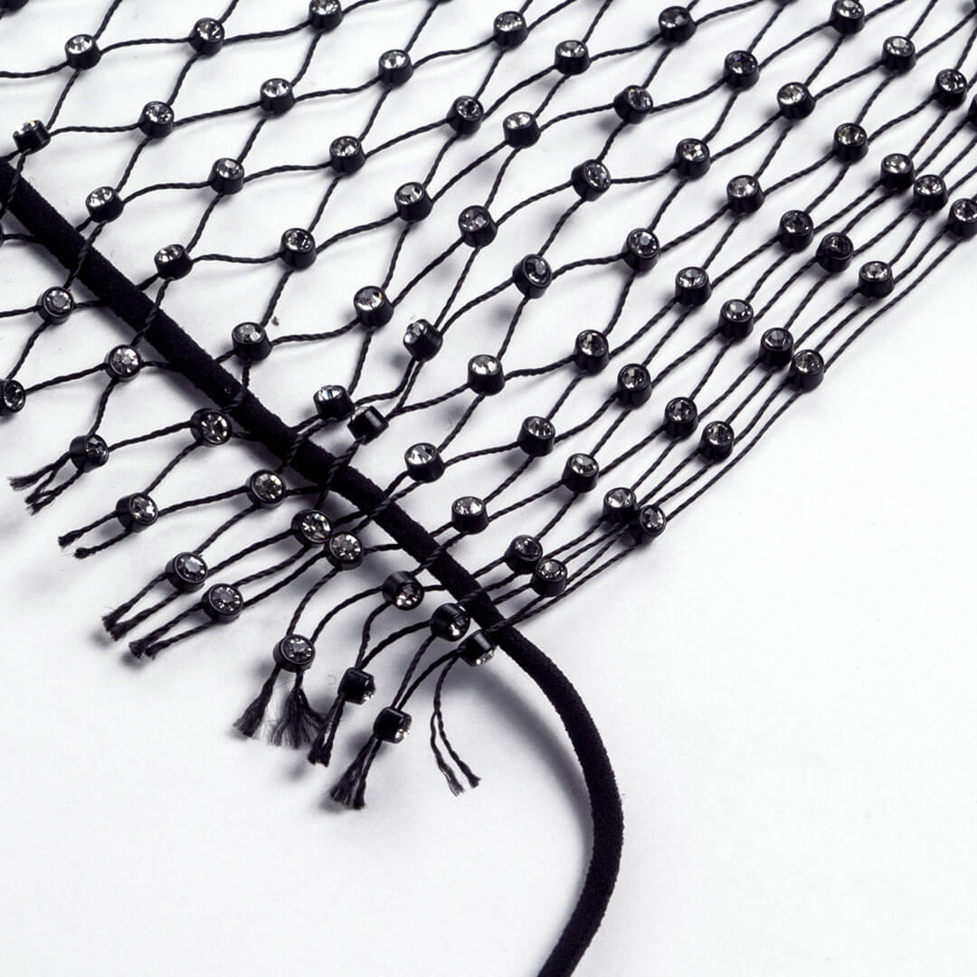 Close-up of the black mesh fabric with scattered rhinestones and fringe.
