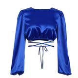 a blue satin cropped top with long sleeves and a tie waist